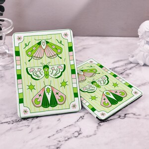 May include: Two white covers with green and pink butterfly illustrations. The covers have a green and white striped border with a pink and white checkered border. The covers have the text "*" on the bottom right corner.