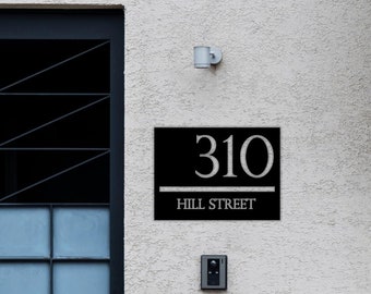 Puede incluir: Un letrero de número de casa en blanco y negro con el número 310 y el texto "HILL STREET" en letras blancas.