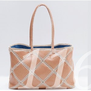 May include: A light brown leather tote bag with a diamond pattern and white stitching. The bag has a blue lining and two top handles.