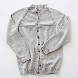 May include: A light gray knitted cardigan with a button-up front and a high collar.