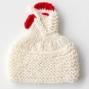 Könnte beinhalten: Weiße Strickmütze mit rotem Hahnenkamm.