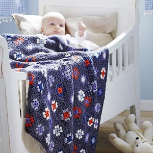Könnte beinhalten: Ein weißes Babybett mit einem Baby, das auf einer gehäkelten Decke mit bunten Blumen liegt. Die Decke ist über die Seite des Babybetts gelegt.