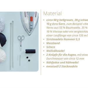 Puede incluir: Un kit de manualidades con tres ovillos de lana en gris, negro y blanco, junto con agujas de tejer, tijeras, una cinta m&eacute;trica y otros suministros de costura. Una plancha es visible en el fondo. La imagen tambi&eacute;n incluye texto en alem&aacute;n.