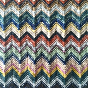 May include: A colorful knitted chevron pattern blanket with stripes of blue, green, yellow, brown, and red.