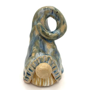 May include: A ceramic gnome figurine with a blue and tan swirled hat and a tan body. The hat curls over the top with a hole in the center. The gnome has a round tan nose and a striped tan and blue bottom.