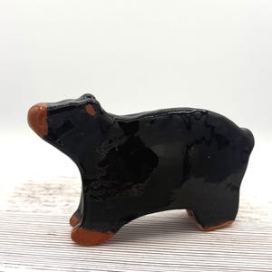 Op de afbeelding: Een keramieken berenbeeldje met een glanzend zwarte afwerking. De snuit en poten van de beer hebben een contrasterende bruine kleur. Het beeldje staat op vier poten.