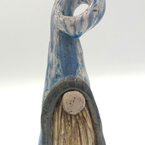 Op de afbeelding: Een keramieken kabouterbeeldje met een blauw-witte swirl hoed en lichaam. De kabouter heeft een bruine baard en een ronde, gespikkelde neus. De hoed buigt in een lus. Het beeldje is handgemaakt.