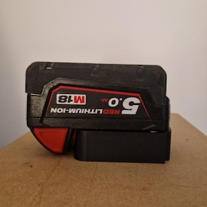 May include: A black and red power tool battery with the text "RED LITHIUM-ION 9.0 Ah M18" on the side.