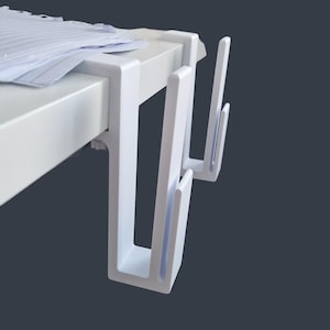 May include: White plastic desk organizers with two hooks each. The organizers are attached to the underside of a white desk.