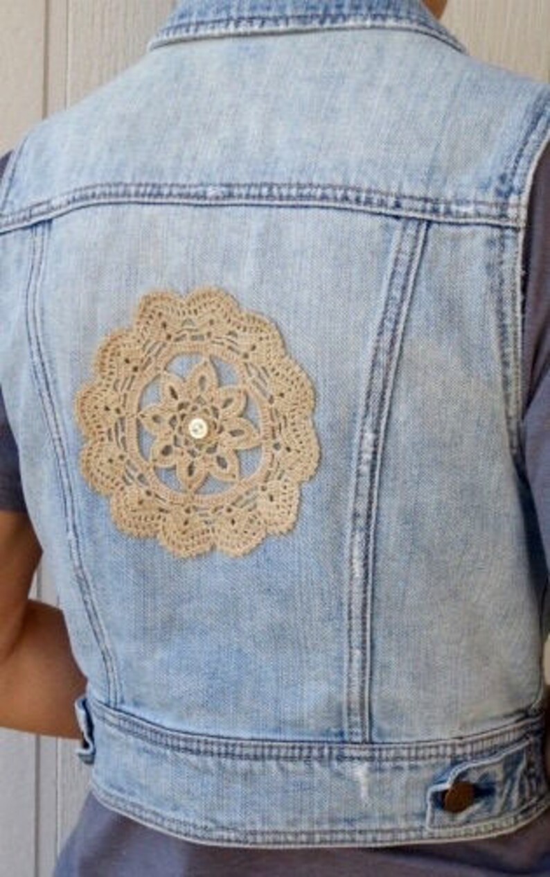 Pu&ograve; includere: Un giubbotto di jeans blu chiaro con un'applicazione di pizzo all'uncinetto sul retro.