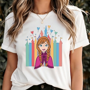 May include: White t-shirt with a colorful illustration of a cartoon girl with red hair and a purple cape in front of a castle with rainbow colored towers and Mickey Mouse balloons.