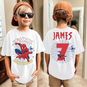 Op de afbeelding: Wit T-shirt met een Spider-Man ontwerp en de tekst "IT'S MY BIRTHDAY" in geel. De achterkant van het shirt toont de naam "JAMES" en het nummer "7" met een Spider-Man afbeelding. Het shirt wordt door een kind gedragen.