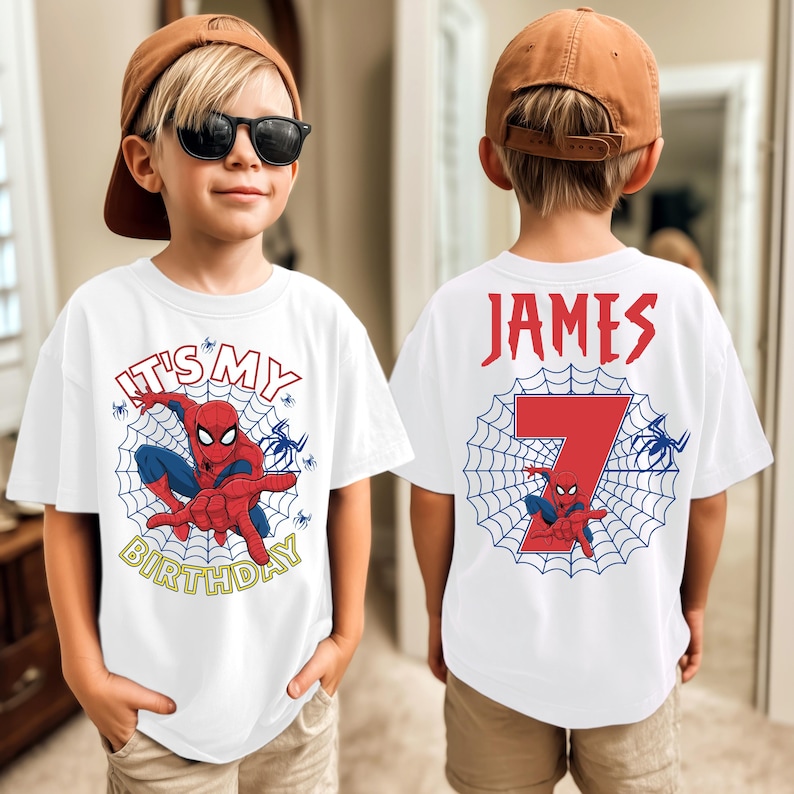 Op de afbeelding: Wit T-shirt met een Spider-Man ontwerp en de tekst "IT'S MY BIRTHDAY" in geel. De achterkant van het shirt toont de naam "JAMES" en het nummer "7" met een Spider-Man afbeelding. Het shirt wordt door een kind gedragen.