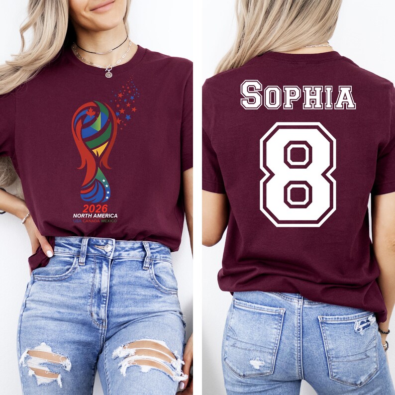 May include: Burgundy t-shirt with a colorful graphic and the text "2026 NORTH AMERICA". The back of the shirt displays the name "SOPHIA" above the number "8" in white. The shirt is made of a soft material.