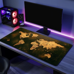 以下が含まれることがあります： 暗い緑色の背景に、金と茶色の世界地図のデザインが施された長方形のデスクマット。 デスクマットは、コンピューターモニター、スピーカー、デスクトップコンピューターを備えたデスクの上に置かれています。