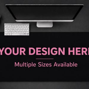 Puede incluir: Alfombrilla de escritorio rectangular negra con el texto "YOUR DESIGN HERE" en rosa. Las palabras "Multiple Sizes Available" están debajo del texto principal. Se ven un monitor de ordenador, un teclado y un portalápices.