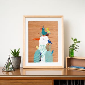 Puede incluir: Una ilustraci&oacute;n enmarcada de un p&aacute;jaro blanco con un p&aacute;jaro azul, verde y amarillo posado en su cabeza. El p&aacute;jaro est&aacute; rodeado de otros p&aacute;jaros, incluyendo un p&aacute;jaro azul, un p&aacute;jaro amarillo y un b&uacute;ho. El fondo es un patr&oacute;n de veta de madera.