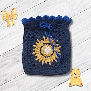 Könnte beinhalten: Ein dunkelblauer Häkelbeutel mit Kordelzug und einem zentralen Sonnenblumenmotiv in Gelb und Weiß. Die Tasche hat einen gewellten oberen Rand und eine passende dunkelblaue Kordel zum Verschließen. Das Design ist quadratisch und handgefertigt.