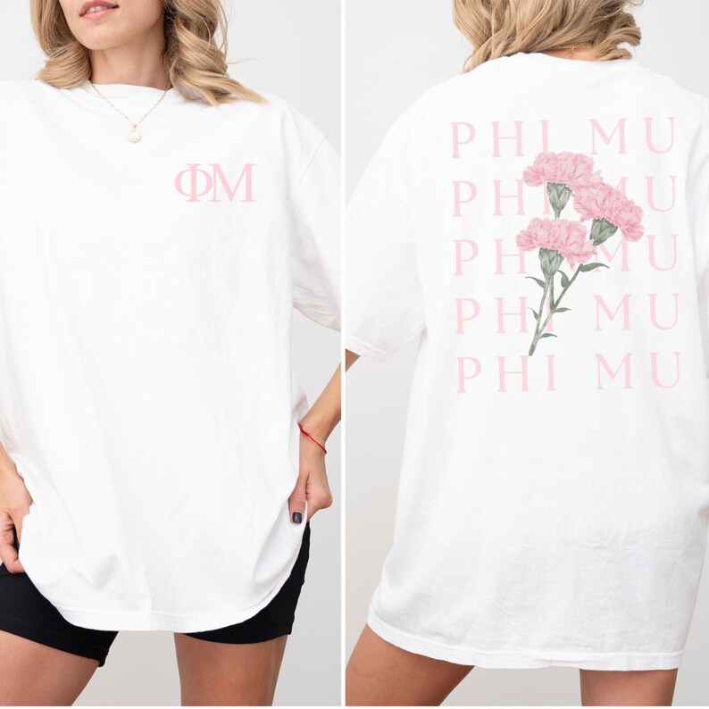 Op de afbeelding: Wit T-shirt met de Griekse letters &Phi;&Mu; in lichtroze op de voorkant. De achterkant van het shirt heeft een bloemenontwerp van roze anjers en de woorden PHI MU in roze.