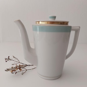 Puede incluir: Cafetera de cerámica blanca con una banda azul claro y ribete dorado. La cafetera tiene un pico y una manija.