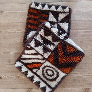 May include: Two brown, white, and orange patterned throw pillows with a fuzzy texture.