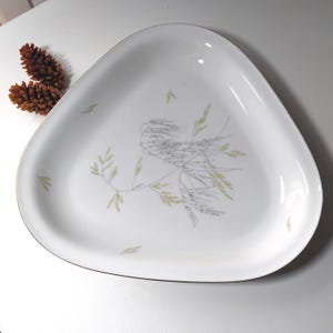 May include: A white triangular serving dish with a gold rim and a delicate design of stylized grass in shades of gray and yellow.