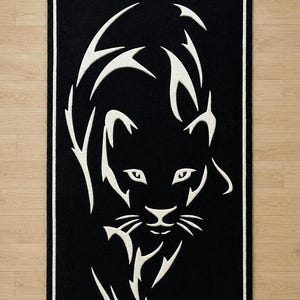 May include: Black rectangular rug featuring a white panther design. The panther is depicted in a stylized, minimalist form, with sharp lines and a bold contrast against the black background. The rug has a white border.
