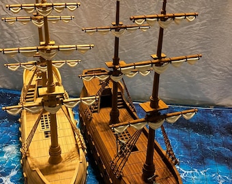 May include: Two wooden model sailing ships. One is light-coloured, the other is a darker brown. Both have multiple masts with white sails and detailed decks. The ships are set against a blue and white patterned surface.