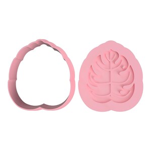 May include: Two pink plastic cookie cutters. One is a leaf-shaped outline, and the other is a leaf-shaped mould with detailed vein impressions. The cutters are designed for baking and crafting.