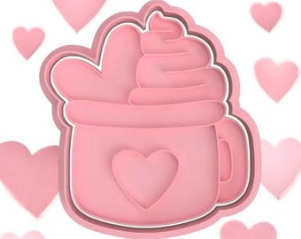 May include: Pink plastic cookie cutter shaped like a mug with whipped cream and a heart on the front.