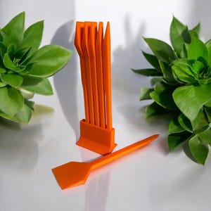 May include: A set of orange plastic tools for prying open electronics, with a separate orange plastic tool with a flat blade.