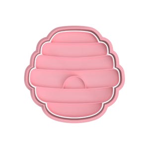May include: Pink plastic cookie cutter shaped like a honeycomb beehive.