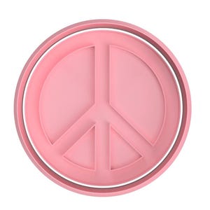 Può includere: Un tagliapasta a forma di segno della pace rosa con un doppio anello attorno al bordo.