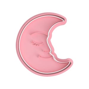 Pode incluir: Cortador de biscoitos em forma de lua crescente rosa com um rosto sorridente e olhos fechados. O cortador tem um contorno branco e é feito de plástico. O design é simples e caprichoso, perfeito para assar guloseimas temáticas.