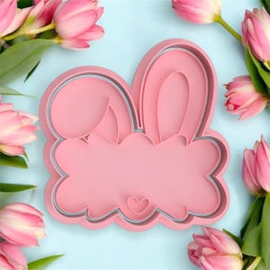 Peut inclure: Emporte-pièce en plastique rose en forme de lapin avec de grandes oreilles et un cœur sur le nez.