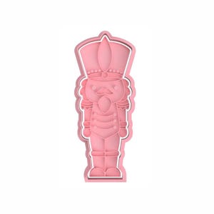 Könnte beinhalten: Rosaer Plastik-Ausstecher in Form eines Nussknackers. Der Nussknacker hat eine weiße Umrandung und ein detailliertes Design.