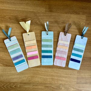 May include: Six colorful bookmarks with different patterns and ribbon ties. Each bookmark has four colored stripes.