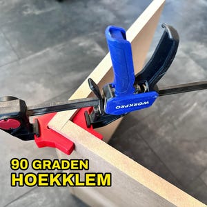 Peut inclure: Un serre-joint d'angle de 90 degrés bleu et noir avec le texte "WORKPRO" sur la poignée bleue. Le serre-joint maintient deux morceaux de bois ensemble à un angle de 90 degrés. Le texte "90 GRADEN HOEKKLEM" est visible sur le bois.