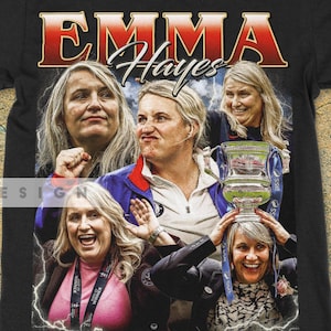 Op de afbeelding: Zwart t-shirt met een retro graphic van Emma Hayes. Het ontwerp bevat meerdere afbeeldingen van haar en de naam "EMMA Hayes" in een rood en wit vintage lettertype. Het shirt heeft een ronde hals en korte mouwen.