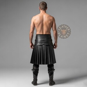 May include: A black leather kilt with pleated design, worn with matching legwear. The kilt features a wide belt and decorative detailing. The image is set against a neutral gray backdrop.
