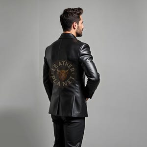 Pu&ograve; includere: Un blazer in pelle nera dal design classico. Il blazer presenta una vestibilit&agrave; sartoriale, revers a lancia e chiusura a due bottoni. La parte posteriore del blazer presenta un logo circolare con la scritta "LEATHER PLANET". Il modello indossa pantaloni neri.