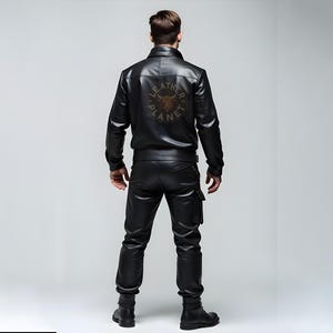 May include: A black leather jacket with a zipper closure and a logo on the back that says "Leather Planet". The jacket has a stand-up collar and long sleeves.