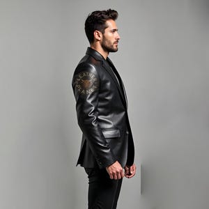 Pu&ograve; includere: Un blazer in pelle nera con revers a lancia e chiusura a un bottone. Il blazer ha un design classico con una vestibilit&agrave; su misura. La manica sinistra presenta un logo circolare con la scritta "LEATHER PLANET". Il modello indossa pantaloni neri.