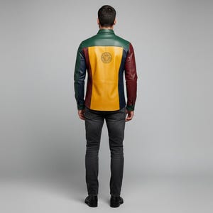 May include: A multi-colored leather shirt with a green, yellow, and burgundy design. The back of the shirt features a circular emblem. The model is wearing dark gray jeans and black shoes. The shirt is a unique fashion statement.