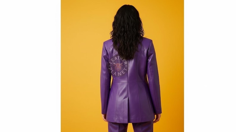 May include: A purple leather blazer with a tailored fit, featuring a logo on the back that reads "LEATHER PLANET". The jacket is paired with matching pants, set against a yellow background.
