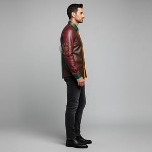 May include: A side view of a person wearing a leather jacket with a burgundy body, brown sleeves, and green and yellow accents. The person is also wearing black jeans and black boots. The background is a solid gray.