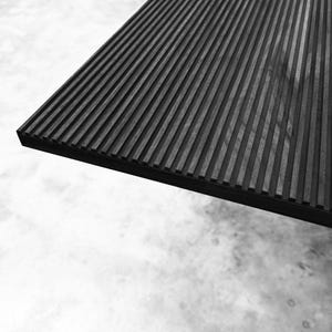 May include: Black wood panel with a grooved texture. The panel is angled and the grooves run horizontally across the surface.