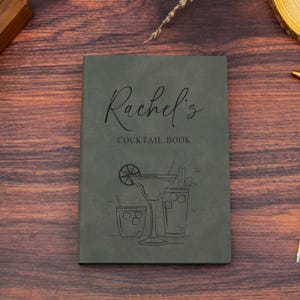 Könnte beinhalten: Ein grünes, ledergebundenes Notizbuch mit dem Text "Rachel's Cocktail Book" und einer Zeichnung von drei Cocktails.