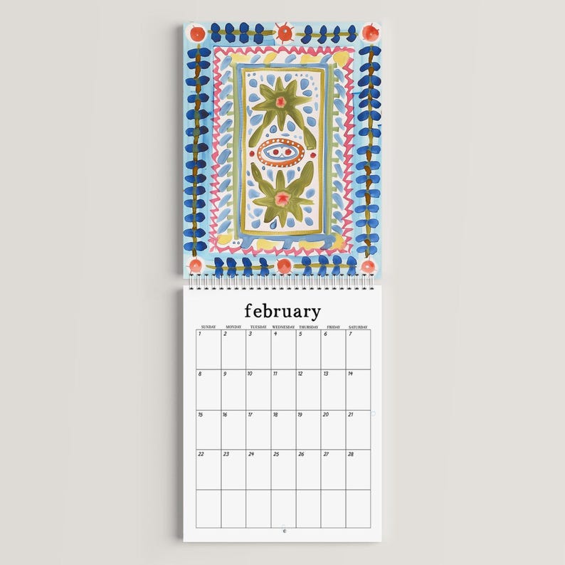 May include: A wall calendar for February with a colorful, abstract design at the top. The design features a rectangular pattern with blue, green, and pink accents. The calendar grid is white with black text.