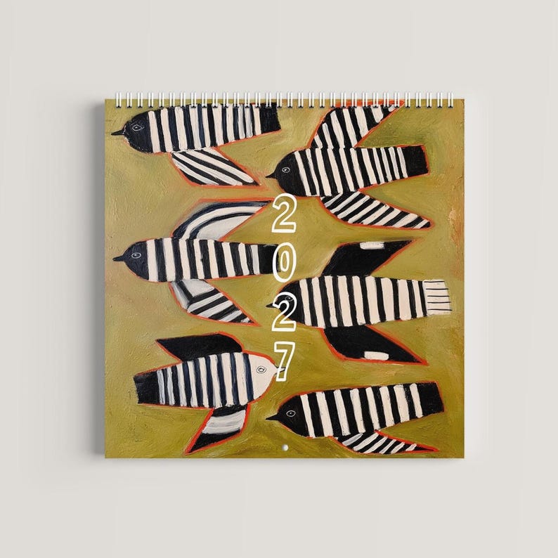May include: A spiral-bound wall calendar featuring a painted olive green background with six stylized birds. Each bird has black and white vertical stripes and thin orange outlines. The year 2027 is printed in white text vertically in the center.